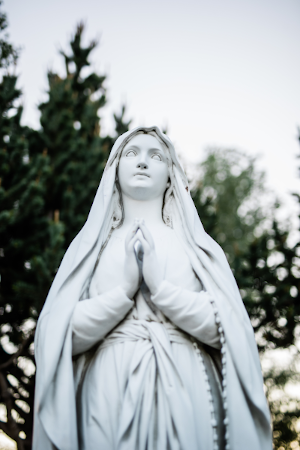 Statue of Mary looking to the sky praying with rosary around her arm